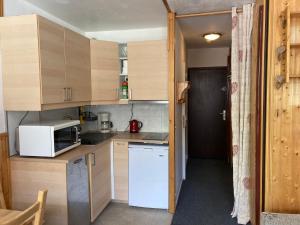 a small kitchen with wooden cabinets and a microwave at Dôme de Polset Appartements VTI in Val Thorens