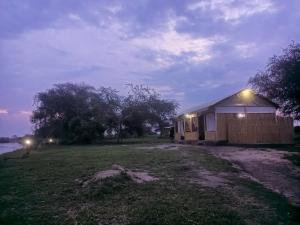 une petite maison avec des lumières sur le côté d'un champ dans l'établissement Semliki Fishing River Camp, 