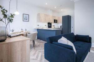 a living room with a blue couch and a kitchen at No 4 Croft House - Luxury 2 Bed Apartment - Tenby in Tenby
