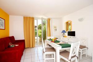 sala de estar con mesa y sofá rojo en Résidence Odalys Le Grand Bleu, en Vendres-Plage