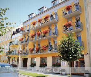 a yellow building with flower boxes on balconies at LD PALACE Spa & Kur in Františkovy Lázně