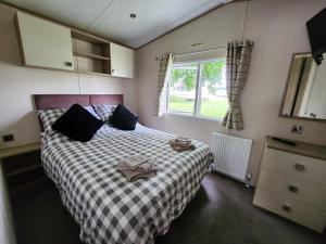 a bedroom with a bed with a checkered blanket and a window at D&A's Short Breaks - St Margarets Bay, Dover in St Margarets at Cliff