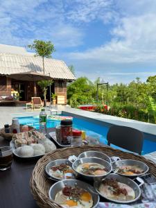 a table topped with plates of food next to a pool at Greyhouse Homestay 