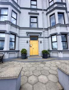 una porta gialla sulla parte anteriore di un edificio di Stunning 3 bed seafront mansion building sleeps 6 adults or 8 with kids a Portrush