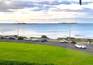 un parcheggio con auto parcheggiate vicino all'oceano di Stunning 3 bed seafront mansion building sleeps 6 adults or 8 with kids a Portrush
