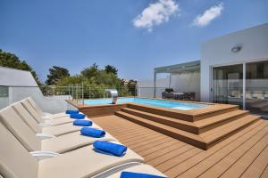 a deck with lounge chairs and a swimming pool at Villa Blu - Family Villa with Indoor heated Pool, Sauna and Games Room in Mellieħa