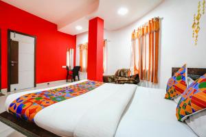 a bedroom with a large bed with red walls at FabExpress Sai Lodging in Nashik