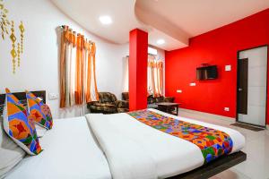 a bedroom with a bed and a red wall at FabExpress Sai Lodging in Nashik