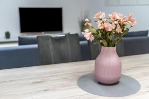 eine rosa Vase mit rosa Blumen auf dem Tisch in der Unterkunft Casa di Michelle in Ringsheim