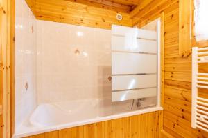 a bathroom with a tub in a wooden wall at Chalet les deux marmottes - Vue montagne in Bolquere Pyrenees 2000