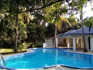 a swimming pool with a house and trees at LeoMar 2 Diani Beach Ferienhaus mit grossen tropischen Garten und Pool in Ukunda