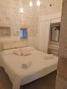 a bedroom with a bed with white sheets and a window at I MaTrulli in Cisternino