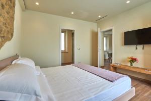 a bedroom with a large white bed and a flat screen tv at Croce di mezzo in Montalcino