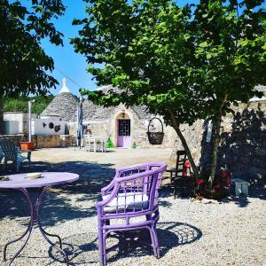 una silla púrpura sentada junto a una mesa en un patio en I MaTrulli, en Cisternino