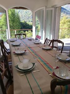 a long table with chairs and plates and glasses at Charming cottage, 10 minutes from Ax les Thermes in Unac