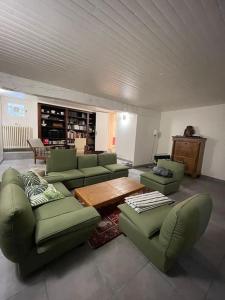a living room with green couches and a wooden table at Charming cottage, 10 minutes from Ax les Thermes in Unac