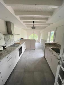 a large kitchen with white cabinets and a tile floor at Charming cottage, 10 minutes from Ax les Thermes in Unac