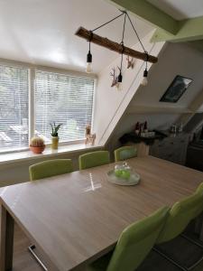 a dining room with a wooden table and green chairs at The Green Apple Durbuy in Durbuy