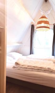 a bed in a room with a window and a chandelier at The Green Apple Durbuy in Durbuy