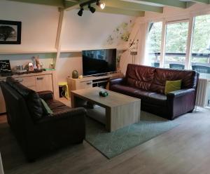 a living room with two leather couches and a coffee table at The Green Apple Durbuy in Durbuy