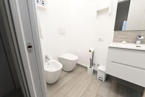a white bathroom with a sink and a toilet at Puntaalarooms in Punta Ala