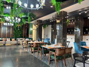 um restaurante com mesas, cadeiras e plantas em Cosmopolitan Hotel em Shymkent