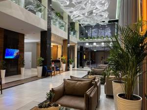 a lobby with couches and plants in a building at Cosmopolitan Hotel in Shymkent
