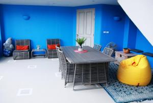 Habitación con mesa, sillas y pared azul. en Chelona Huahin Khao Tao, en Ban Thung Kham