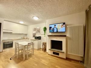 a kitchen with a table and a tv on the wall at La Finestra sul Brenta con POSTO AUTO PRIVATO AL CENTRO di MAD di Campiglio CIPAT O22233-AT-O13262 in Folgarida