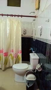 a bathroom with a toilet and a shower curtain at Green Garden Homestay in Giritale