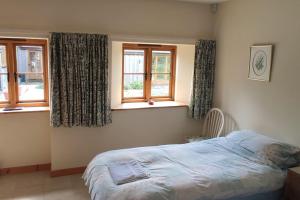 a bedroom with a bed and two windows at Spacious Luxury barn conversion - next to Tarka Trail cycle path in Great Torrington