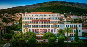 ein großes Gebäude vor einer Stadt mit einem Berg in der Unterkunft Hilton Imperial Dubrovnik in Dubrovnik