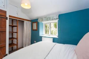 1 dormitorio con cama blanca y pared azul en Hurdler's Cottage, en Shipston on Stour