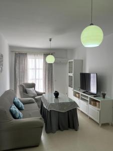 Una sala de estar con un sofá, una mesa y un televisor. en Apartamento Plata Real, en Sanlúcar de Barrameda