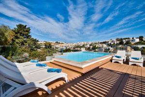 a patio with a swimming pool and chairs on a deck at Villa Goa - By Luxury Villas Malta in Mellieħa