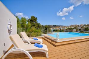a deck with two chairs and a swimming pool at Villa Goa - By Luxury Villas Malta in Mellieħa