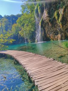 a wooden bridge over a body of water with a waterfall at Guesthouse Nikolina in Korenica