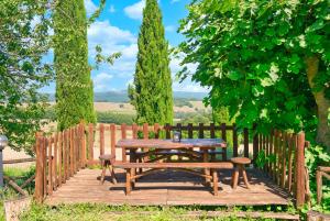 una mesa de madera y sillas en una terraza de madera en Agriturismo Galgani - Historical Medieval House with Exclusive Pool and Park, en Chiusdino