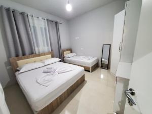 - une chambre avec 2 lits dotés de draps blancs et d'un miroir dans l'établissement Twins Apartment, à Përmet