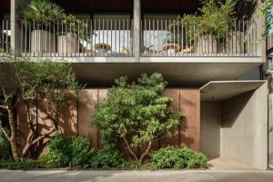 un edificio con un albero di fronte a una recinzione di TRUNK(HOTEL) YOYOGI PARK a Tokyo