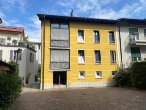 ein gelbes Gebäude mit weißen Fenstern auf einer Straße in der Unterkunft Yellow House Guest House in Mendrisio