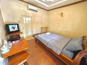 Schlafzimmer mit einem Bett, einem TV und einem Tisch in der Unterkunft โรงแรมแสงทองรีสอร์ท in Ban Nam Mong