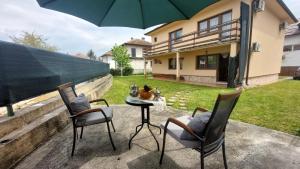 a patio with two chairs and a table with an umbrella at Holiday Home Ilidza in Sarajevo