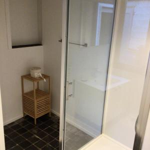 um chuveiro numa casa de banho com uma porta de vidro em Black and white em Profondeville