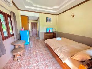 a bedroom with a bed and a table and a television at โรงแรมแสงทองรีสอร์ท in Ban Nam Mong