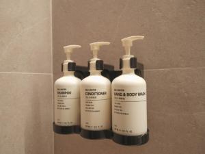 three bottles of shampoo and body wipes on a wall at Hotel 1900 Chinatown in Singapore