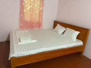 a bed with a wooden frame and white sheets at Tuệ Nhi Homestay Ngườm Ngao Bản Giốc in Cao Bằng +66 photos