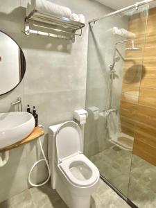 uma casa de banho com um WC e uma cabina de duche em vidro. em MIDMOST CASA em Can Tho