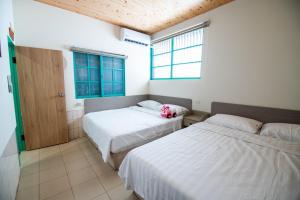 1 dormitorio con 2 camas y ventana en 家暖暖,老屋新生,房源內有戶外空間,嘉義市民宿013號, en Chiayi