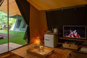 a room with a tent with a tv and a table at CAMP CAYLA - EDEN in Chiang Mai